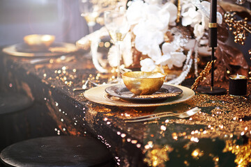 Christmas table setting with plates, silverware, gift box and decorations in black and gold colors