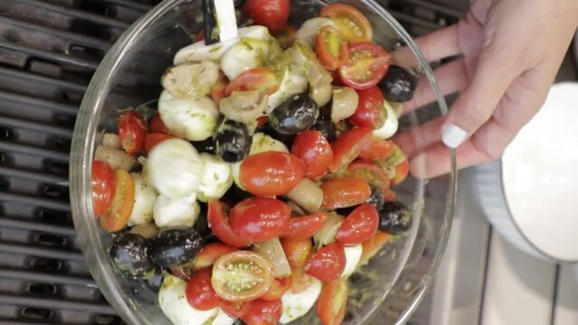 Joven mujer prepara ensaladas en un embase de cristal, Vista Vertical.