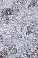 Shiny heavily wrinkled metal silver gray foil vertical texture background for design