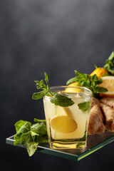 Fototapeta Refreshing summer cocktail with ice, ginger, lemon, and mint. obraz