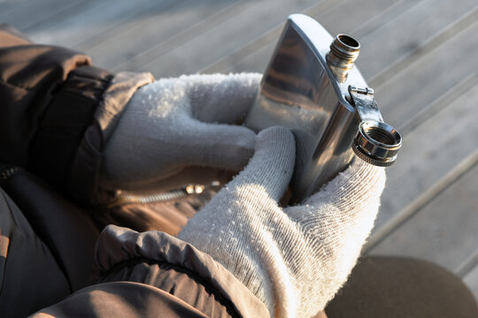 Shiny steel pocket flask in hands of a man, outdoor photo