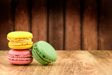Three colorful macaroons on wooden background