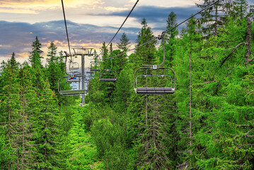 Lift in the mountains. Tourist double lift above the forest on the mountain slope.