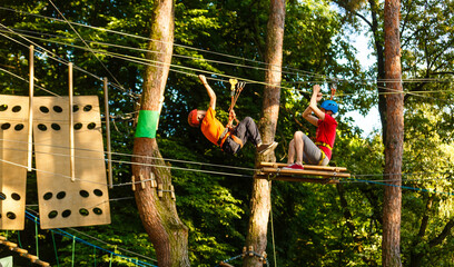 male instructor helps the child on the rope road in the training camp.
