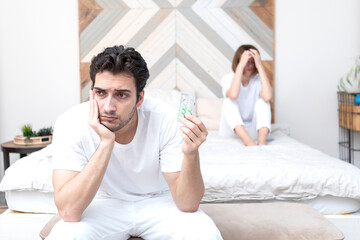 Frustrated and depressed man sitting on the edge of the bed and holding tablets for strength after...