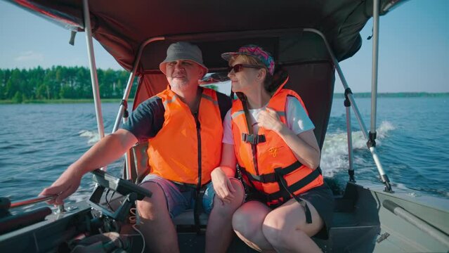 Caucasian middle-aged man and woman ride a motor boat on the lake