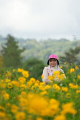 Portrait of Asian woman in a yellow flower garden and enjoying its beauty