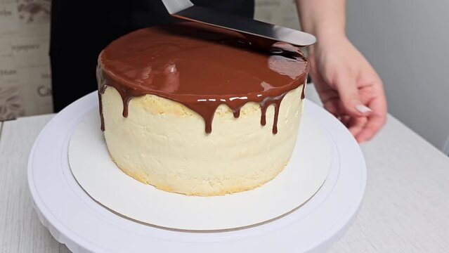 A female pastry chef pours liquid chocolate