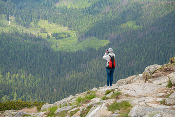 Young woman traveler on a high mountain with a photo camera.