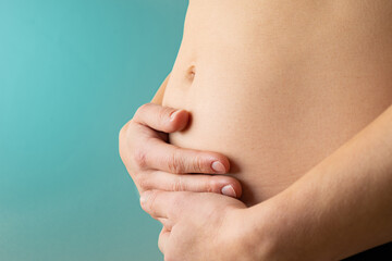 Very close up view of woman in first months of pregnancy gently holding her belly. Pregnancy first...