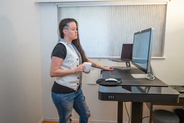 Woman stading at her ergonomic desk from her home office.
