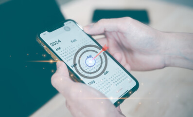 Concept of financial target planning and reminder for 2024. man using smartphone working with calendar 2024, business planning marketing and investment