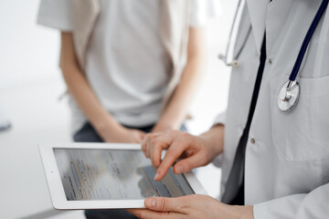 Doctor and child patient. The doctor is using tablet computer and is ready to examine the boy. The concept of ideal health in medicine.