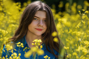 Portrait of a beautiful young woman surrounded by canola flowers.