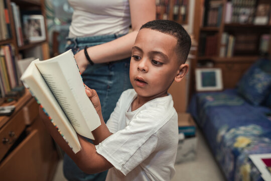 African boy choosing a book from a bookshelf at home