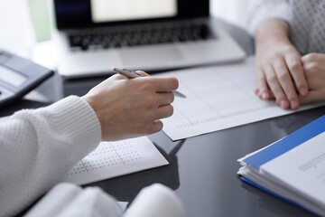 Woman accountant using a calculator and laptop computer while counting taxes for a client. Business audit concepts.