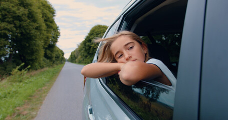 Pensive girl looked out the window car on backseat feeling sadness. Tired little school kid traveling back home from long summer vacations in a car.