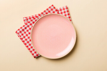 Top view on colored background empty round pink plate on tablecloth for food. Empty dish on napkin with space for your design