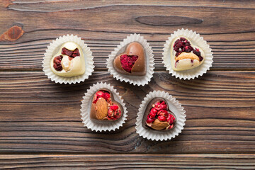 chocolate sweets in the form of a heart with fruits and nuts on a colored background. top view with space for text, holiday concept