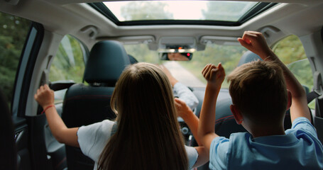 Two little boy and girl listens enjoys music and dancing while road trip. Children are playing in...