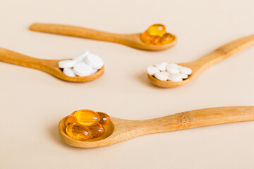 Vitamin capsules in a spoon on a colored background. Pills served as a healthy meal. Red soft gel vitamin supplement capsules on spoon