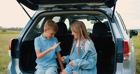 Boy and girl playing sit car trunk happiness. Cute little kid having fun. Honeymoon enjoy vacation...