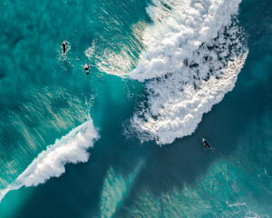 Aerial view of the ocean with surfers, wave and nice pristine blue water