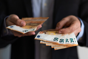 Close up view of a business man holding and counting fifty euros bank notes