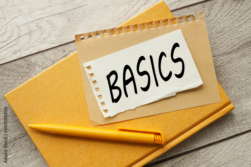 Poster basics text on torn paper on yellow notebook light wooden background.