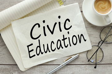 CIVIC EDUCATION On a wooden background, a notepad with text with a cup of coffee and glasses