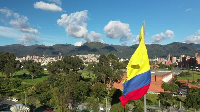 Colombian flag flying on a flagpole with a view of the city of Bogot&aacute; in the background