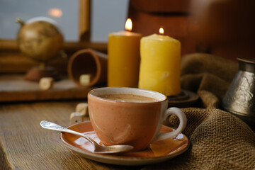 cup with drink coffee on old vintage wooden table, metal coffee maker, candles burn, caffeine improves functioning of human brain, stimulates nervous system, health benefits and harms, copy space