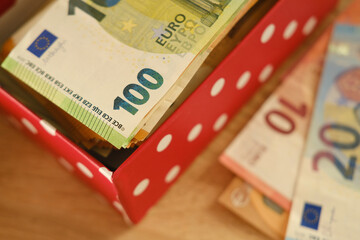 close-up box with family savings, cash 50, 20 euro banknotes on table, concept gift for holiday,...
