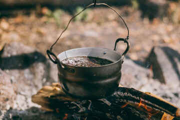 Hiking pot, Bowler in the bonfire. soup boils in cauldron at the stake. Traveling, tourism, picnic...