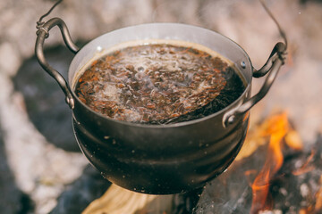 Hiking pot, Bowler in the bonfire. soup boils in cauldron at the stake. Traveling, tourism, picnic...