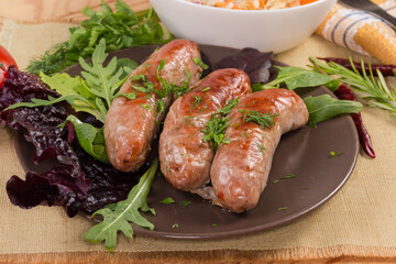 Baked sausages with leaf vegetables on brown dish close-up