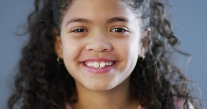Face, smile of latino girl and closeup happy against blue background. Proud or happiness, portrait of a confident kid and excited or cheerful headshot of female person smiling in a studio backdrop