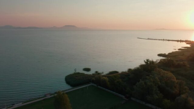 Panoramic view of Lake Balaton in Hungarian Green areas and Port of Fonyod during Sunrise, Central Europe. Aerial perspective of Transdanubian region as tourist destination. 4k drone shot
