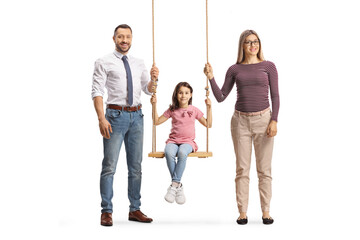 Fototapeta premium Full length portrait of a man and woman standing next to girl on a wooden swing