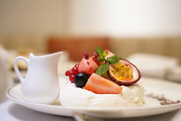 A fine dining dessert in a fancy restaurant. White breakfast with fruits and syrup.  