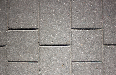 Gray background of a brick pavement.Background of a block of gray stone tiles Surface of a gray brick.Stone pavement slab texture. Road,tile,concrete slab.