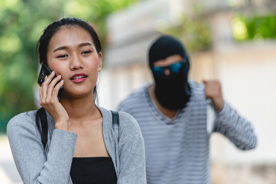 Thief Robber in mask with knife trying to snatch backpack handbag from woman victim. Bandit snatching mobile phone from a young girl crimes on city street concept.