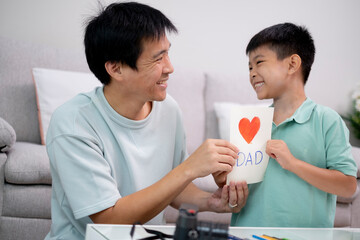 Asian son give his father a card love dadwith red heart shape  in father's day occationary with...