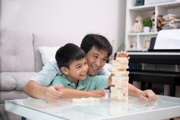 Senior Asian Father play wood toy with his son with smile of happiness, relationship and takinktime with kid in family.