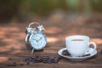 black drip coffee in ceramic cup on old wood table with coffee bean. Barista serve cup of hot black coffee on old wooden table cafe shop in garden with coffee bean.