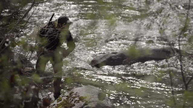 Pescatore  in azione durante una battuta di pesca a spinning. Pescare su un torrente montano in Trentino, Italia.