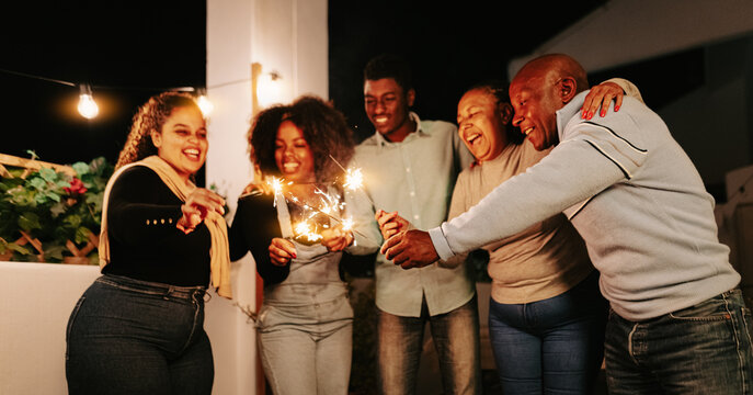 Happy African family celebrating with sparklers fireworks at house party - Parents and holidays concept