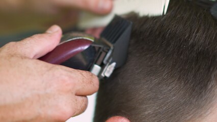 barber using clippers to cut a young man's hair