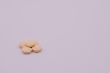 Stack of pale colored pills on a white background