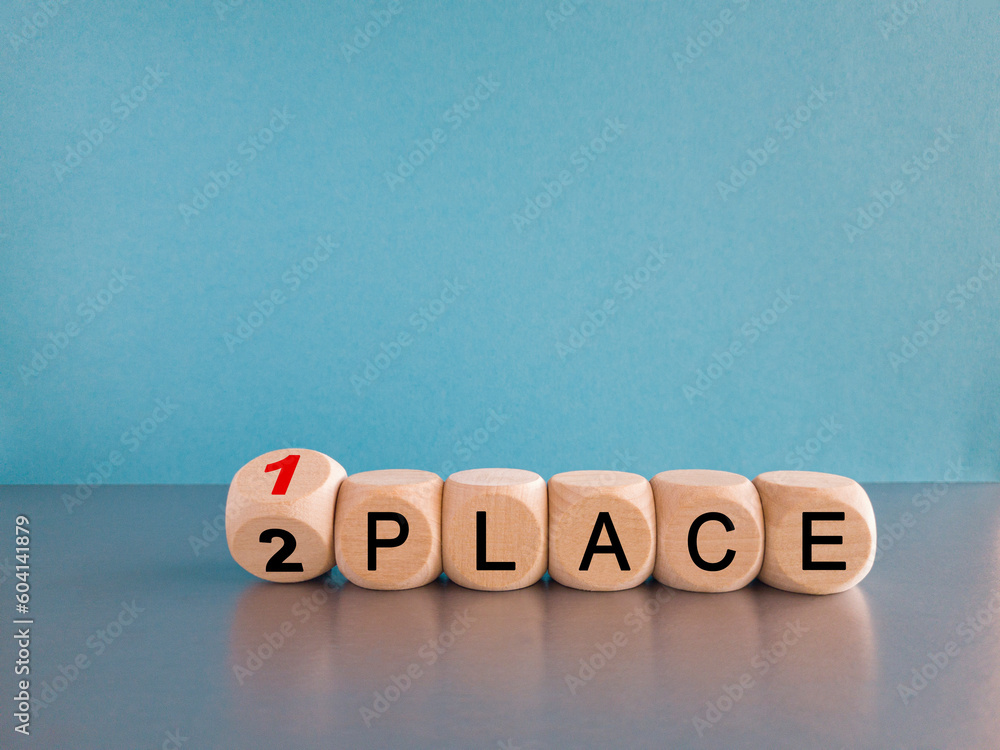 Wall mural From 2 to 1 place symbol. Turned wooden cubes and changes concept words 2 place to 1 place. Beautiful gray table blue background. Business and from 2 to 1 place concept. Copy space.